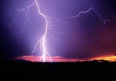 Highly electric lightning strike with horizontal filament at sunset