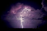Storm lit from within by lightning flashes and an anvil lightning strike