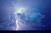 A brilliant lightning bolt jumps out from the top of a storm cloud