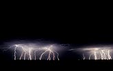 Many lightning discharges line the distant horizon