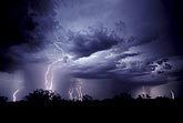Distant bolts and intra-cloud lightning flashes accentuate cloud detail