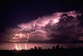 Two anvil bolts leap from a cloud lit by interior lightning flashes