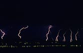 Distant cloud-to-ground lightning strikes over city lights