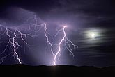 Bright lightning beside the full moon shining through clouds