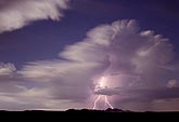 Lightning and moonlight illuminate a storm cloud with soft detail