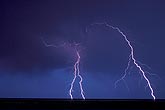 Forked and diagonal lightning bolts punctuate a blue a twilight