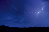 Delicate sparking lightning filaments skip across a mountain twilight
