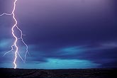 A single highly electric lightning bolt with purple storm clouds