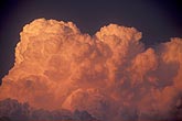 Cumulonimbus towers billow in the glow of a red sunset
