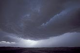 A low dark cloud arcs through the stormy sky