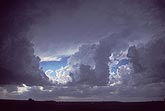 Large shaded Cumulus clouds near a storm