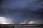 Dark cloud and sweeping rain advance over an arid landscape
