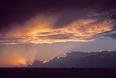 Gold-lined clouds in a dusky sunset, with anvils lit by the sun’s rays