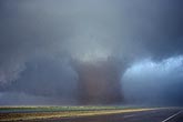 A wide wedge tornado surrounded by cloud tags in the wall cloud base