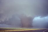 A large wedge tornado stands like a thick tree trunk in the sky