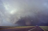 A supercell storm with circular wall cloud and tornado is pulling away