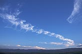 A train of cloud tufts trails across a deep blue sky