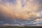 A slender high rainbow arc in golden twilight 