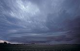 A brooding storm cloud hangs low over a desolate landscape