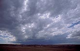 A woolly cloud sheet leads toward dark clouds in a distant storm