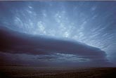 Smooth dark arc of cloud beneath a cloud deck stippled by turbulence