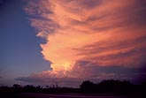 Sunset washes a Cumulonimbus anvil cloud in a dusky red light