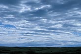 Cloud billows over rolling hills in a tranquil landscape