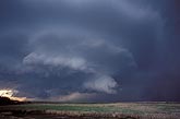 A dark storm with a brushy lowering looms over a remote landscape