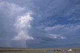 Sunlit shafts of rain fall near the tall updraft tower of a severe storm