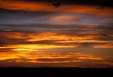 Abstract: red and gold cloud bands cross a sunset sky