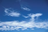 Abstract: cloud tufts rise above a band of wispy cloud