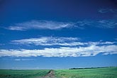 A strip of tufted clouds drifts over a rural landscape