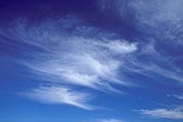 Wispy clouds race forward in a deep blue sky