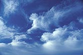 Dreamy skyscape with dense tufts of cloud in a deep blue sky.