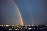 A double rainbow with a secondary bow over a city