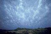 Mammatus clouds bedeck an aging storm anvil over mountains