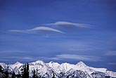 Two peculiar wave cloud patches, like spaceships over mountains