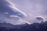 Silvery patches of lenticular wave clouds over mountains