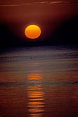 The sun disk, darkened by haze, over water
