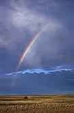 A bright partial rainbow arc adds enchantment to a stormy sky