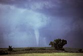 Slender, white cone tornado with sky brightened by clear slot