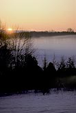 Sunrise blanket of fog on snowy fields