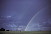 A rainbow arcs high over ranchland