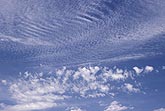 Cloud tufts scatter across a finely textured stippled cloud background