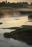 Fog hovers over a river in a mysterious sunrise landscape