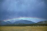 A low horizontal rainbow arcing over misty mountains