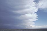 A thick storm anvil’s flanges mark changes with time
