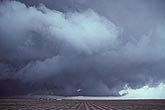 A newly plowed field lies under a dark cloud