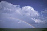 A rainbow arcs in front of a storm cloud