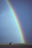 A bright, tall rainbow arcs down on a remote farm
